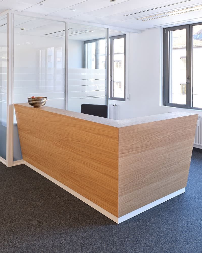 Großzügiger Eingangsbereich mit maßgefertigtem Empfangstresen aus Holz von der Echaz Schreinerei