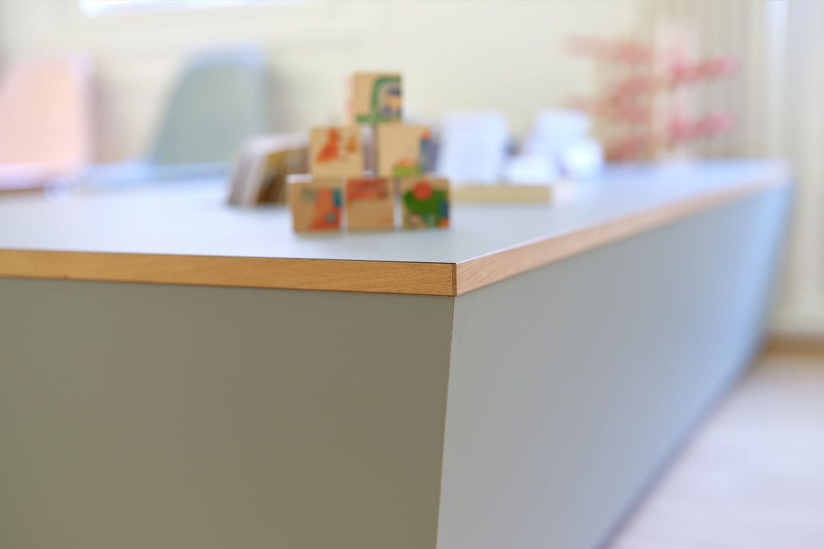Detailansicht eines maßgefertigten Empfangstresens mit Holzoberkante, gefertigt von einer Schreinerei für den Praxisausbau