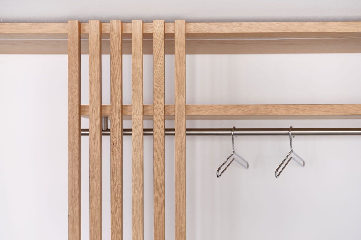 Detailansicht einer maßgefertigten Bürogarderobe mit Holzlamellen und Kleiderstange aus der Echaz Schreinerei