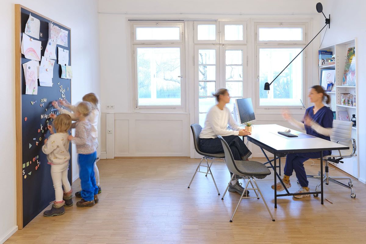 Besprechungsraum einer Praxis mit maßgefertigter Holz-Magnetwand, umgesetzt von einer Schreinerei für individuelle Praxismöbel