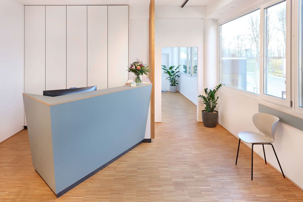 Maßgefertigter Empfangstresen mit Holzoberfläche in einer Praxis, realisiert von der Echaz Schreinerei