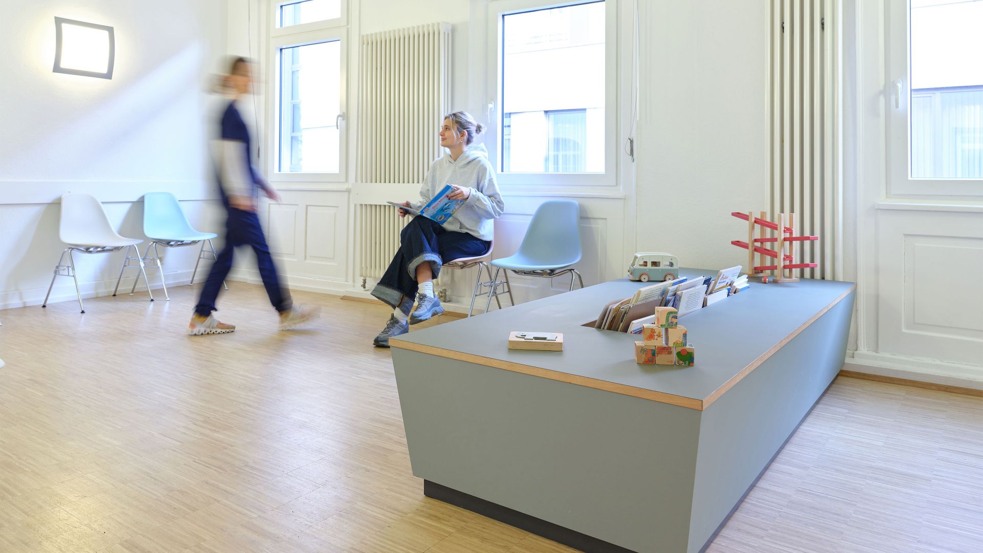 Heller Wartebereich einer Praxis mit maßgefertigten Holzmöbeln und Spieltisch, geplant und gefertigt von einer Schreinerei